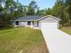 Single story home with gray siding, white garage door and grassy yard at 1280 Nw Redwood Dr, Dunnellon, FL 34431