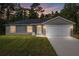 Newly constructed home with gray siding, white garage door, and grassy lawn at 1280 Nw Redwood Dr, Dunnellon, FL 34431