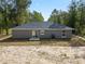 Rear view of a house with gray siding and a sliding glass door at 1280 Nw Redwood Dr, Dunnellon, FL 34431