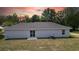 Rear view of home with sliding glass doors and large backyard under colorful sky at 5363 Nw 3Rd St, Ocala, FL 34482
