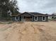 New construction home with gray siding, a black roof, and white trim ready for landscaping at 5411 Nw 7Th Pl, Ocala, FL 34482