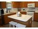 Kitchen with island, white appliances, and wood cabinets at 9662 Sw 97Th Ln, Ocala, FL 34481