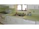 Kitchen boasts white cabinets, light green countertops, and a double sink at 10470 Sw 99Th Ave, Ocala, FL 34481