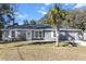 Gray house with solar panels, palm tree, and grassy yard at 19173 St Benedict Dr, Dunnellon, FL 34432