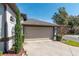 Attached garage with beige door and landscaping at 2011 Se Twin Bridge Cir, Ocala, FL 34471