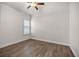 Bedroom with wood-look floors, ceiling fan, and plantation shutters at 5015 Belted Kingfisher Dr, Oxford, FL 34484