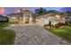 Elegant home at dusk featuring a three-car garage and lush landscaping at 7549 Nw 33Rd Pl, Ocala, FL 34482