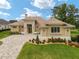 Tan house with tile roof, three-car garage, and landscaped yard at 7549 Nw 33Rd Pl, Ocala, FL 34482