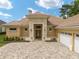 Tan house with tile roof, three-car garage, and landscaped yard at 7549 Nw 33Rd Pl, Ocala, FL 34482