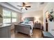 Main bedroom with a ceiling fan, large windows, and gray wood flooring at 7617 Sw 96Th Avenue Rd, Ocala, FL 34481