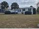 Single-story manufactured home with deck and landscaped yard at 8009 County Road 109D, Lady Lake, FL 32159