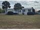 Single-story home with deck and palm trees in front yard at 8009 County Road 109D, Lady Lake, FL 32159