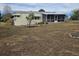 Back of house with screened porch, deck, and manicured lawn at 8009 County Road 109D, Lady Lake, FL 32159