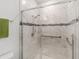 Walk-in shower featuring glass doors, marble-look tiling, and a gray tile accent stripe at 10871 Sw 62Nd Avenue Rd, Ocala, FL 34476