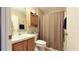 Cozy bathroom featuring wood cabinets and a shower with neutral-toned curtain at 17096 Se 96Th Chapelwood Cir, The Villages, FL 32162