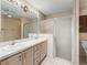 Bathroom features a double sink vanity, a glass-door shower, and decorative wallpaper at 17163 Se 76Th Boxbury Ct, The Villages, FL 32162