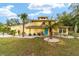 Yellow house with palm trees, landscaped yard, and turquoise door at 19785 Se 156Th St, Umatilla, FL 32784