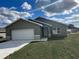 Newly built home with gray siding, white garage door, and small lawn at 24300 Sw Sea Cliff Ave, Dunnellon, FL 34431