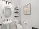 Stylish powder room with pedestal sink, floating shelves, and round mirror at 9229 Sw 52Nd Place Rd, Ocala, FL 34481