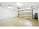 Spacious garage with an epoxy floor, a large garage door, and plenty of storage space at 8990 Se 178Th Muirfield Pl, The Villages, FL 32162