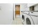 Laundry room area featuring tile floors, washer, dryer, and a view into the garage at 8990 Se 178Th Muirfield Pl, The Villages, FL 32162