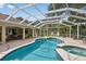 Enclosed pool area featuring a jacuzzi, mature landscaping, and ample lounge space at 8990 Se 178Th Muirfield Pl, The Villages, FL 32162