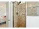 An elegant glass door enclosed shower features decorative tile, a handheld shower, and safety bar at 8990 Se 178Th Muirfield Pl, The Villages, FL 32162