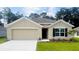 Charming single-story home featuring a two-car garage, neutral stucco, a dark front door, and manicured landscaping at 10012 Se 161St Lane Rd, Summerfield, FL 34491