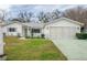 White single-story house with a two-car garage and well-maintained lawn at 10882 Sw 62Nd Ave, Ocala, FL 34476