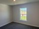 A clean bedroom featuring gray carpet, light gray walls, and a view of the outdoors at 2154 Nw 23Rd Loop, Ocala, FL 34475