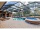 Spacious screened pool and hot tub with brick coping and lounge chairs at 7267 Se 12Th Cir, Ocala, FL 34480