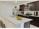 Modern kitchen with dark brown cabinets, stainless steel appliances, and an island at 8511 Las Palmas Way, Wildwood, FL 34785