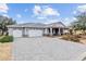 Gray house with stone accents, 3-car garage, and landscaped front yard at 8749 Sw 93Rd Cir, Ocala, FL 34481