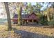 Rustic red house with covered porch sits on a grassy lot, surrounded by large trees at 876 Ne 71St Ln, Ocala, FL 34479