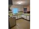 L-shaped kitchen featuring white cabinets and patterned wallpaper at 9359 Bahia Rd, Ocala, FL 34472