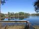 Beautiful view of the lake from the backyard, framed by a wooden deck railing and a bright blue sky at 13055 Ne 7Th Loop, Silver Springs, FL 34488