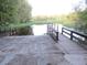 Concrete boat ramp and dock offer access to a serene lake surrounded by lush greenery at 13099 Ne 7 Loop, Silver Springs, FL 34488