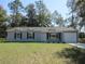 Beautiful single-story home with gray siding, black shutters, and a well-kept lawn at 13099 Ne 7 Loop, Silver Springs, FL 34488