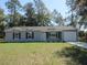 Attractive single-story home featuring a gray exterior, dark shutters, and a neatly maintained lawn at 13099 Ne 7 Loop, Silver Springs, FL 34488