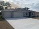 Gray three-car garage home with a long concrete driveway and a neat front yard at 15155 Sw 52 Cir, Ocala, FL 34473