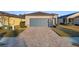 Tan one-story house with gray garage door, landscaped yard, and paver driveway at 7752 Sw 96Th Avenue Rd, Ocala, FL 34481