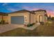 Tan one-story house with gray garage door, landscaped yard, and paver driveway at 7752 Sw 96Th Avenue Rd, Ocala, FL 34481