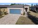 Tan one-story house with gray garage door, landscaped yard, and paver driveway at 7752 Sw 96Th Avenue Rd, Ocala, FL 34481