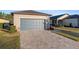 Tan one-story house with gray garage door, landscaped yard, and paver driveway at 7752 Sw 96Th Avenue Rd, Ocala, FL 34481