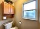 Bathroom toilet with wooden cabinets, open shelf and a frosted glass window at 15715 Sw 11Th Terrace Rd, Ocala, FL 34473