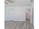 Bedroom with gray wood floors, closet, ceiling fan and view into hallway at 16434 Se 57 Pl, Ocklawaha, FL 32179