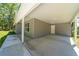 Covered carport area showcasing ample space, concrete flooring, and an exterior door at 16450 Se 57Th Pl, Ocklawaha, FL 32179