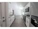 Modern kitchen with stainless steel appliances and white cabinets opening to dining area at 16450 Se 57Th Pl, Ocklawaha, FL 32179