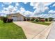 Tan house with a two-car garage, driveway, and landscaped yard at 17606 Se 93Rd Butler Ct, The Villages, FL 32162