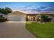 Tan one-story house with a two-car garage and well-maintained lawn at 17606 Se 93Rd Butler Ct, The Villages, FL 32162